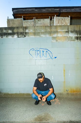 Sam Weber crouching against a graffiti wall